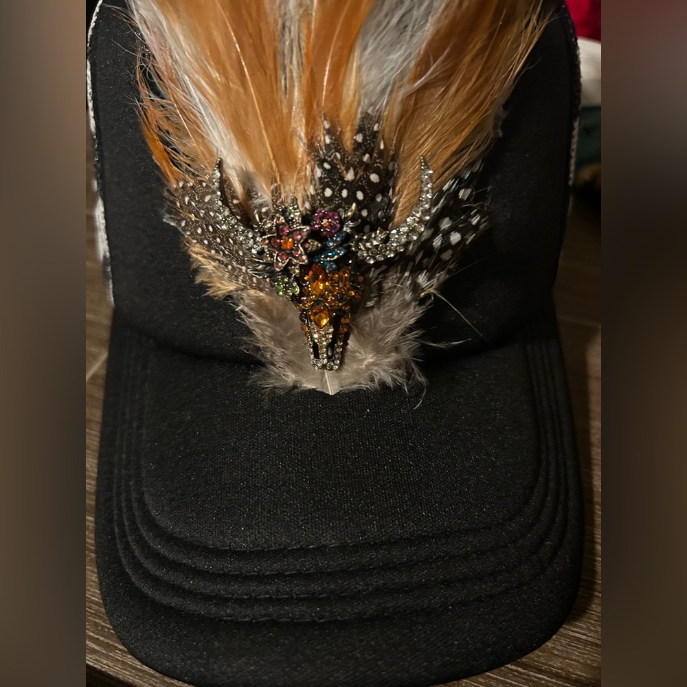 Feathered trucker hat with bull skull broach.